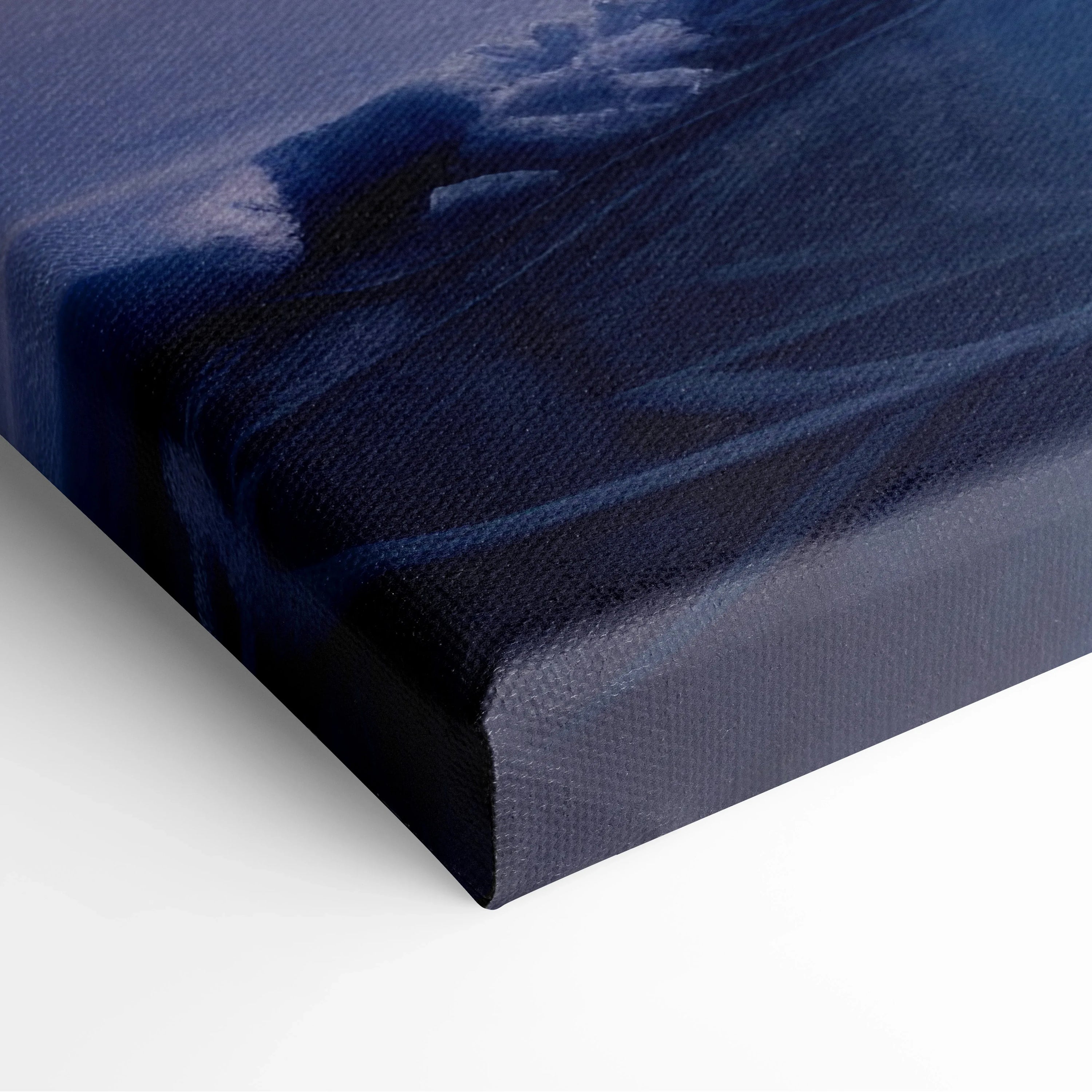 Close-up of wrapped canvas edge showing textured fabric and dark blue tones of snowy sunset winter landscape wall art.