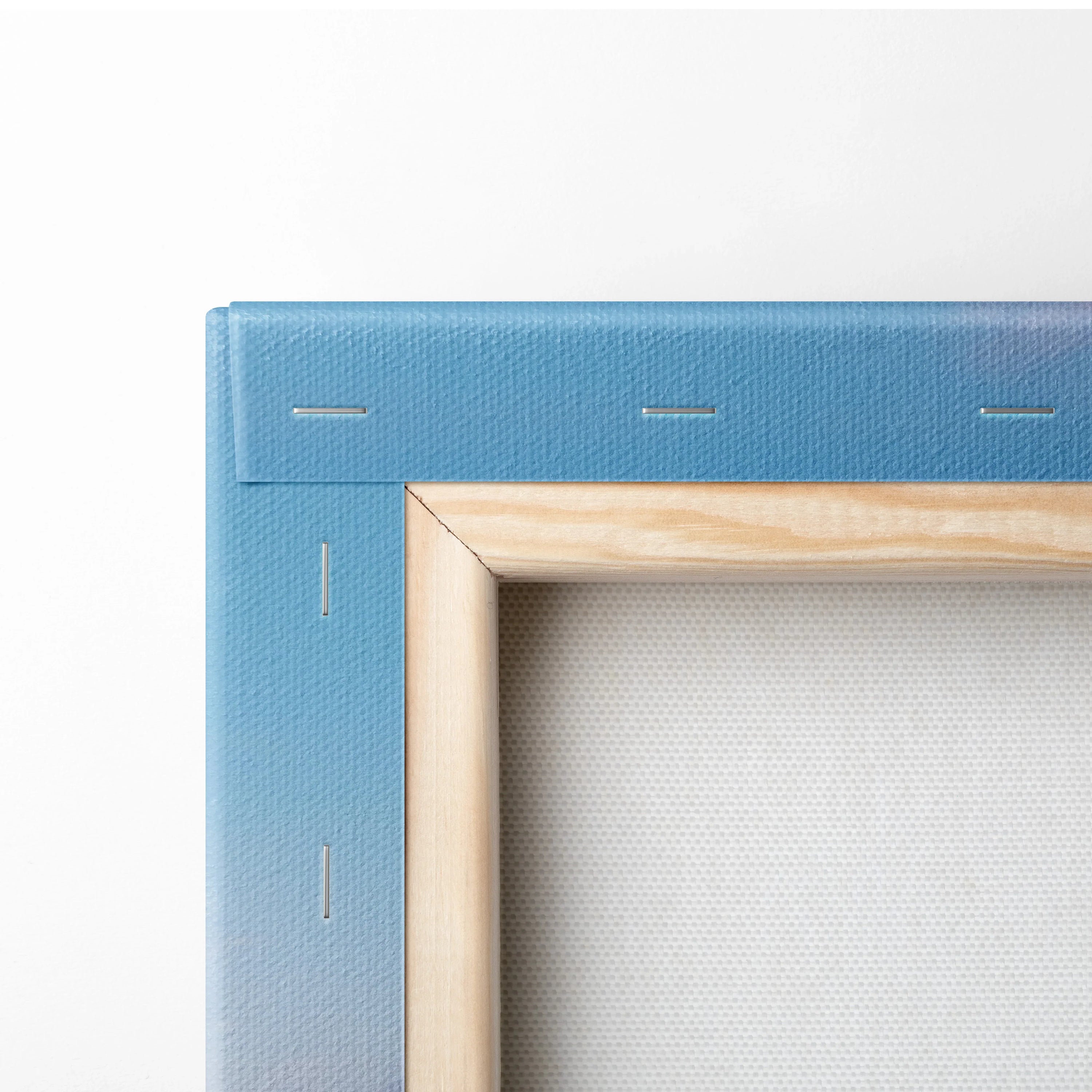 Blue gradient stretched canvas corner with wooden frame and visible staples on white background.