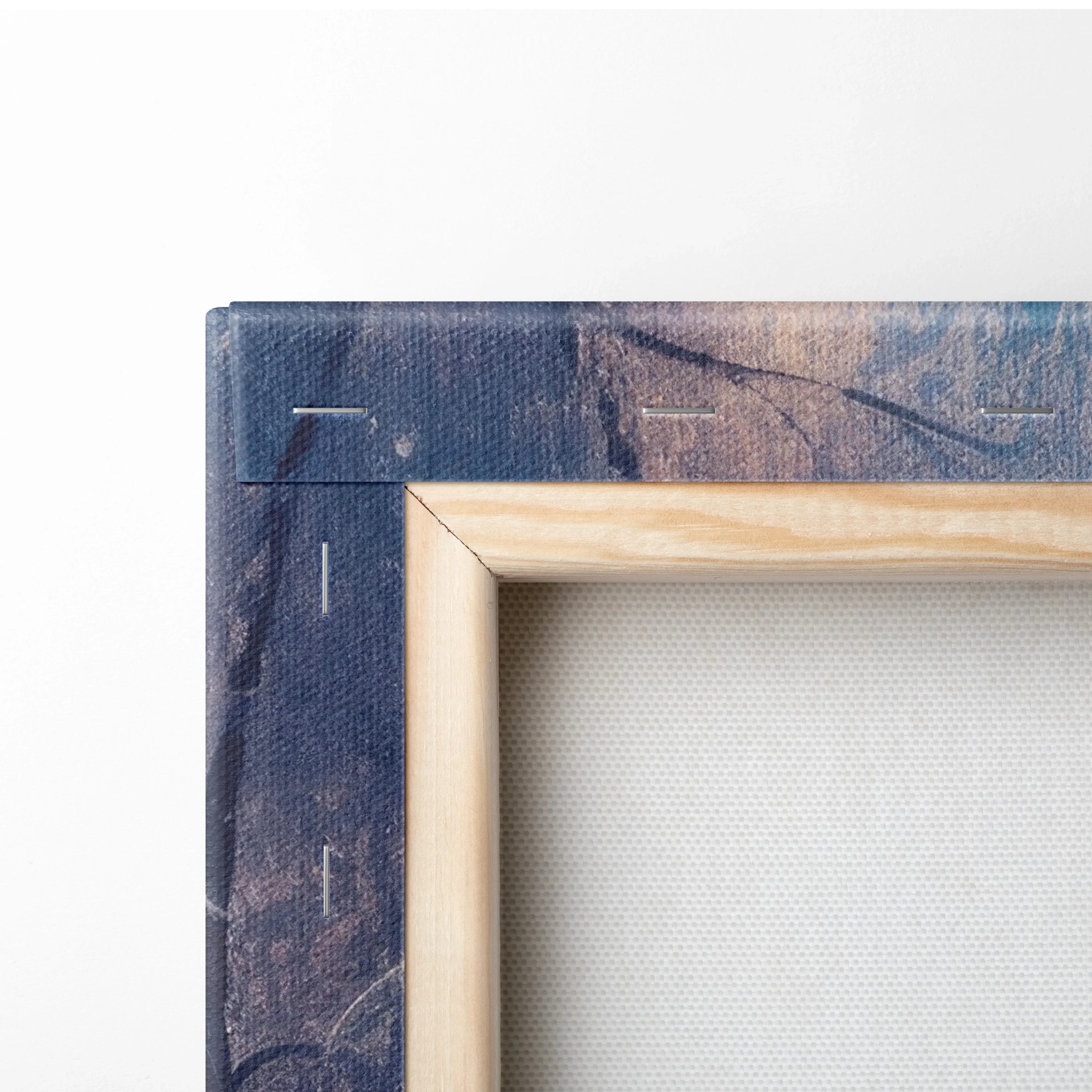 Close-up view of canvas art edge with wooden frame and dark blue printed sides showing fabric texture.
