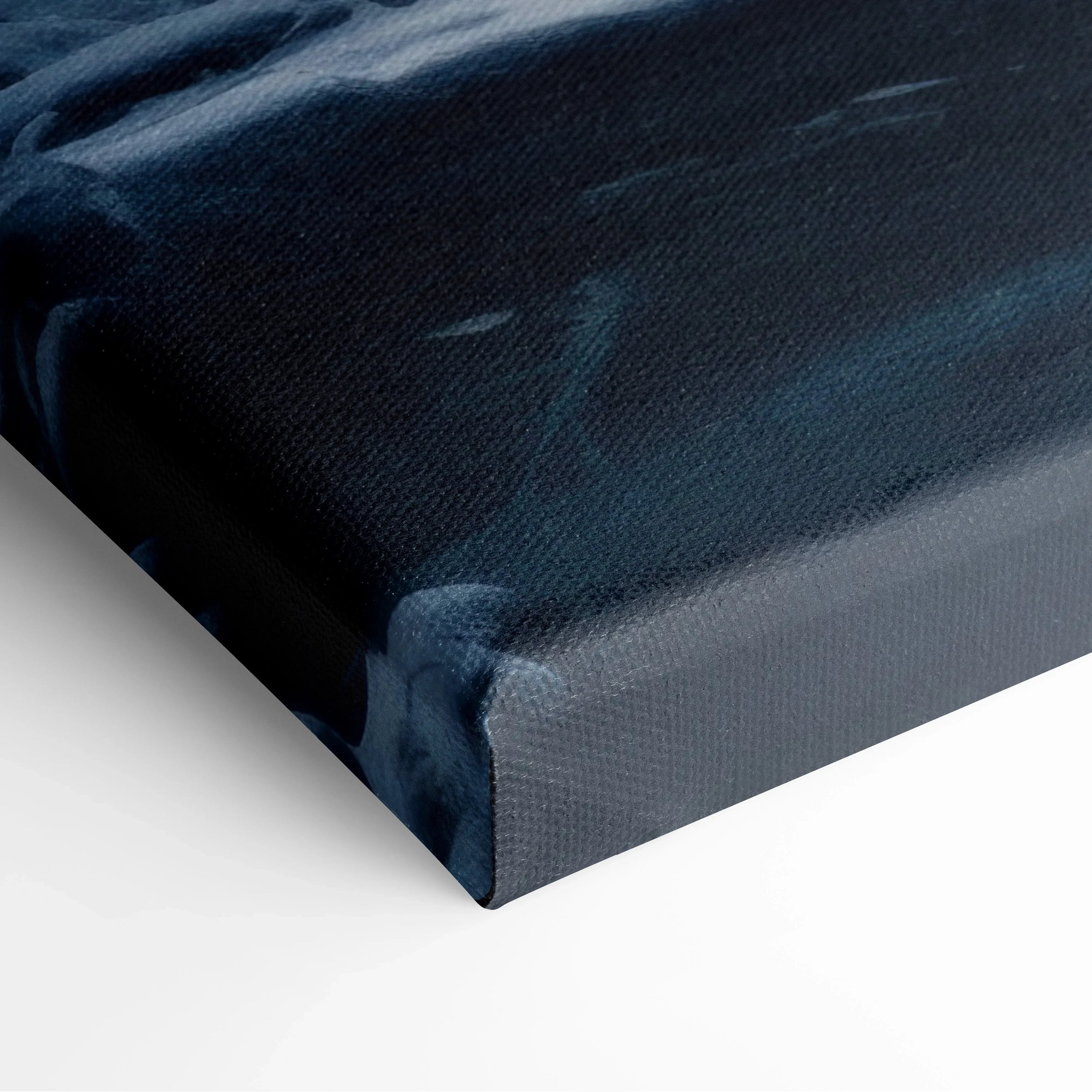 Close-up of corner of canvas wall art showing a dark blue and white snowy forest river scene with textured fabric surface.