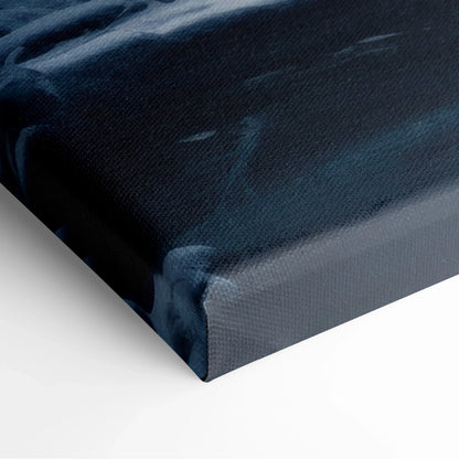 Close-up of corner of canvas wall art showing a dark blue and white snowy forest river scene with textured fabric surface.