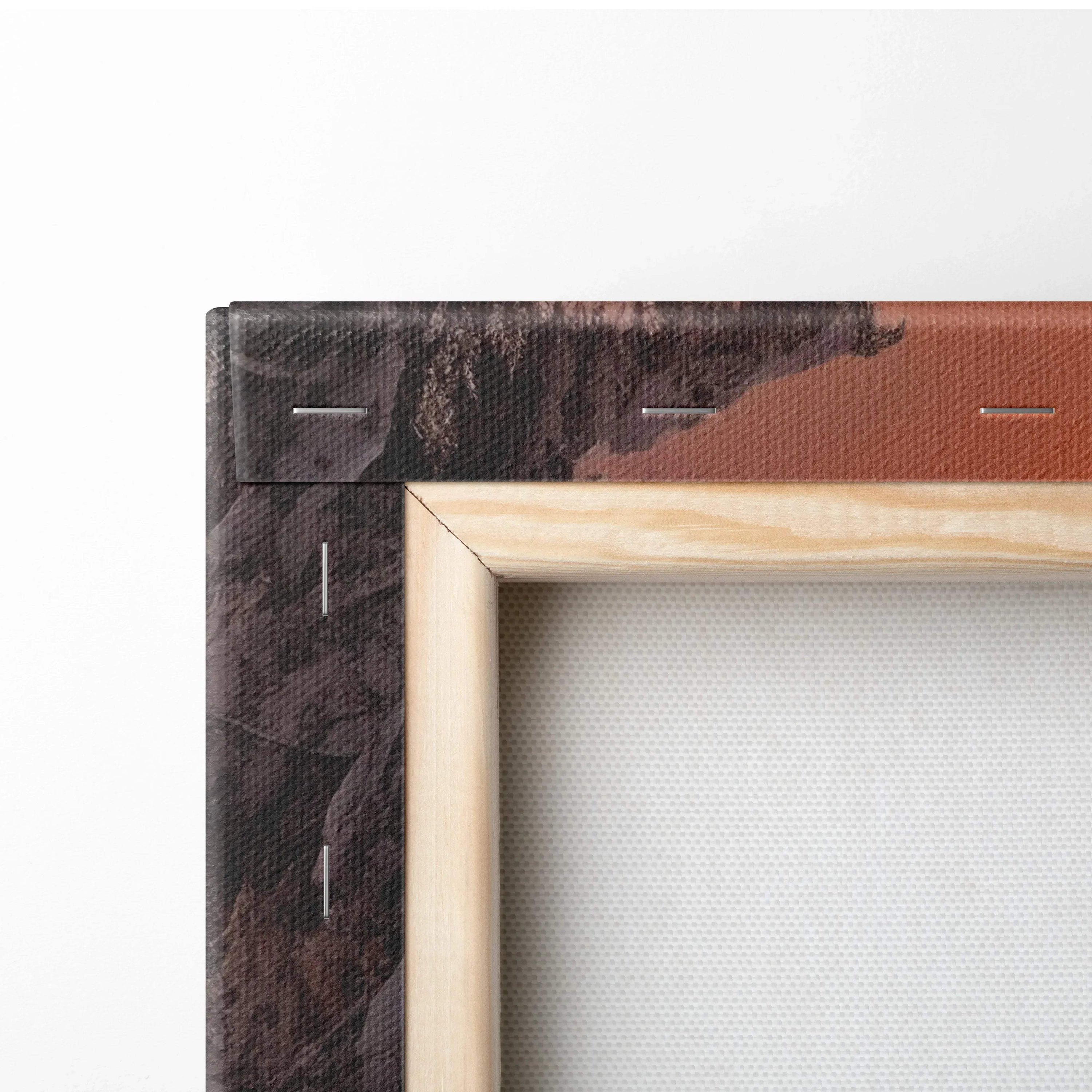 Close-up of wooden frame corner with white canvas stretched tightly, showing brown and black printed edge of winter sunset.