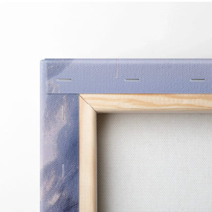 Close-up of wooden-framed canvas with purple and blue painted edges showing snow and sunset hues.