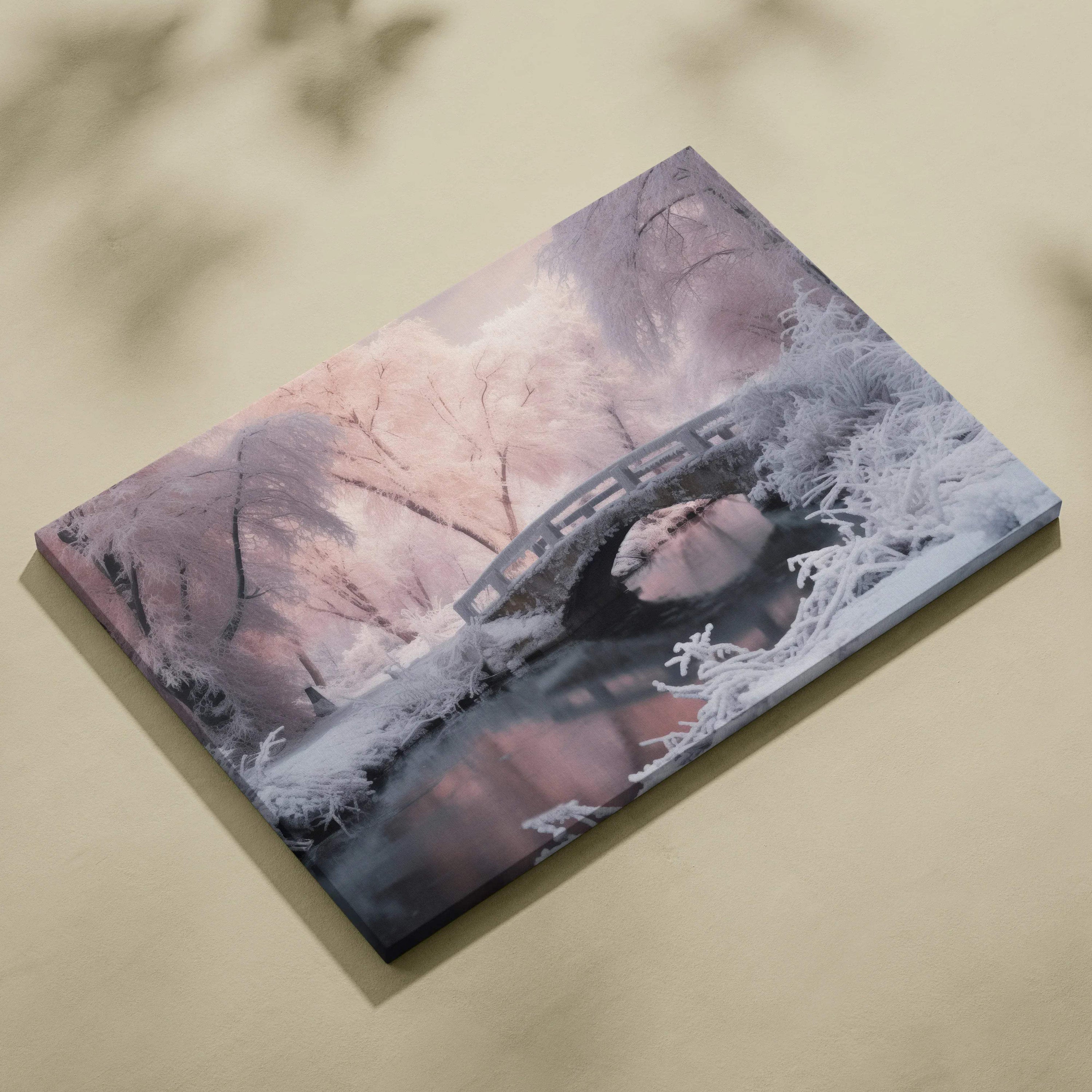 Canvas wall art depicting a serene snowy bridge over a reflective stream at dusk with soft purple and pink tones.