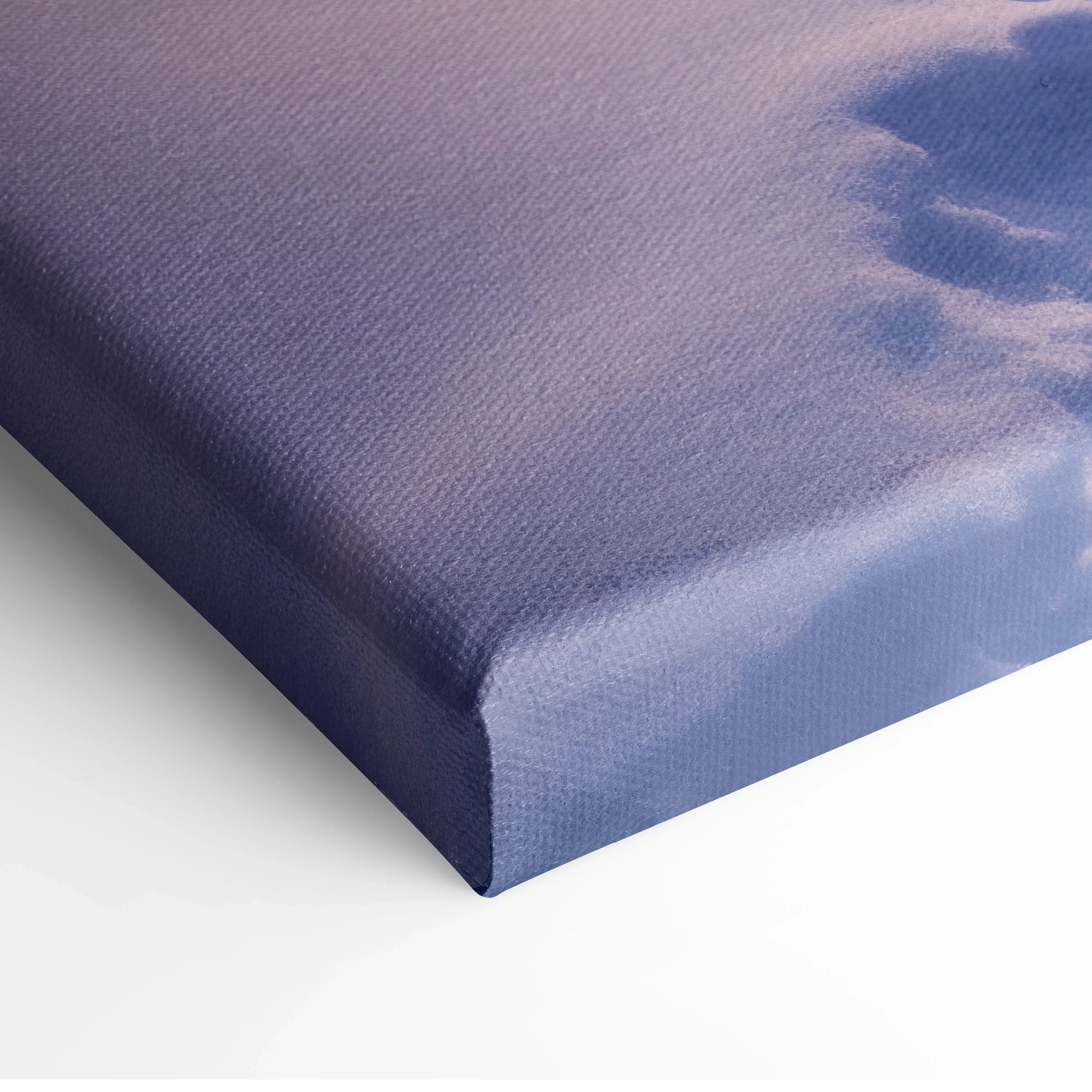 Close-up of canvas wall art with textured fabric showing a winter sunset scene in soft purple and pink tones.