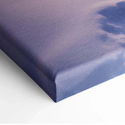 Close-up of canvas wall art with textured fabric showing a winter sunset scene in soft purple and pink tones.
