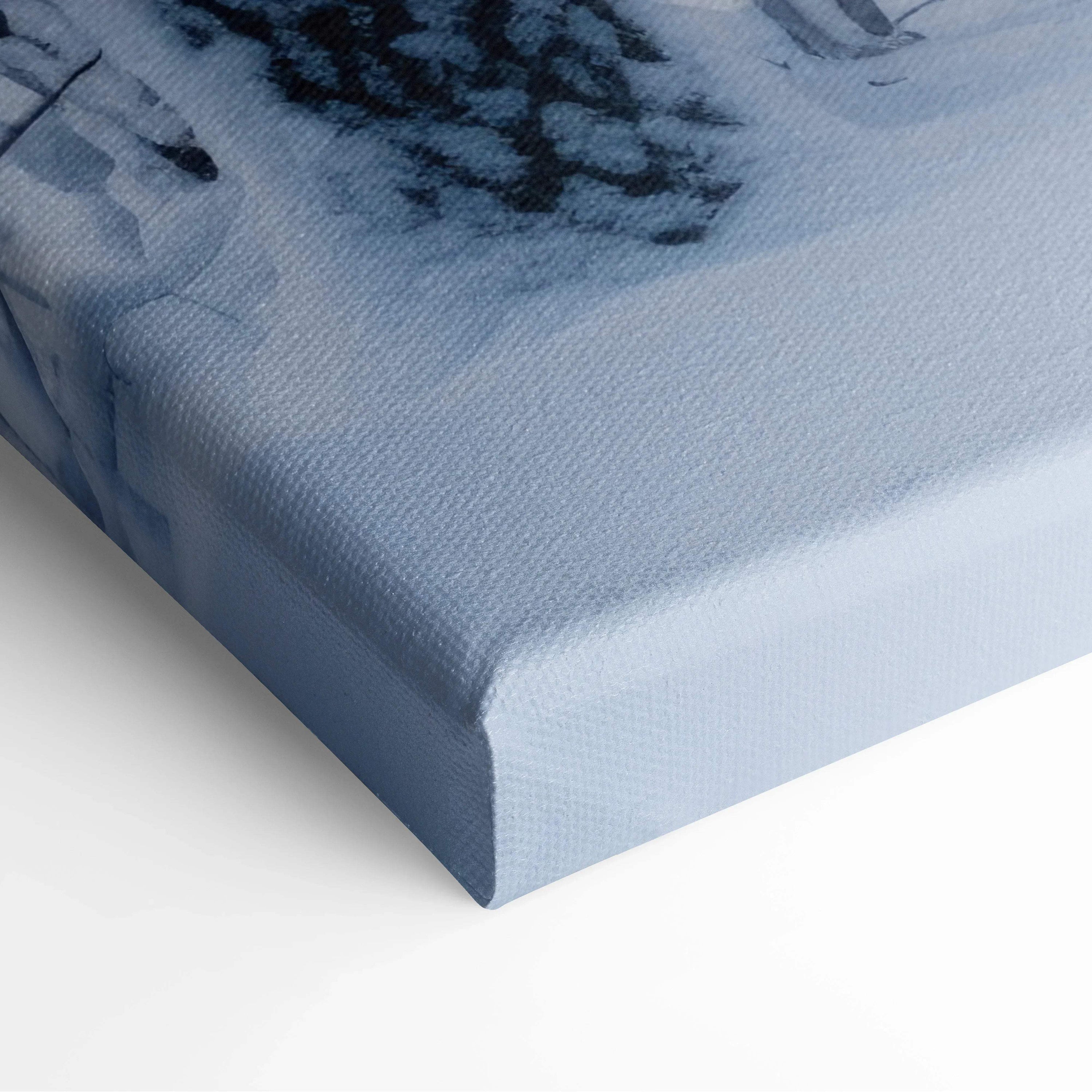 Close-up of canvas wall art featuring a winter forest scene with snowy trees in soft blue tones.