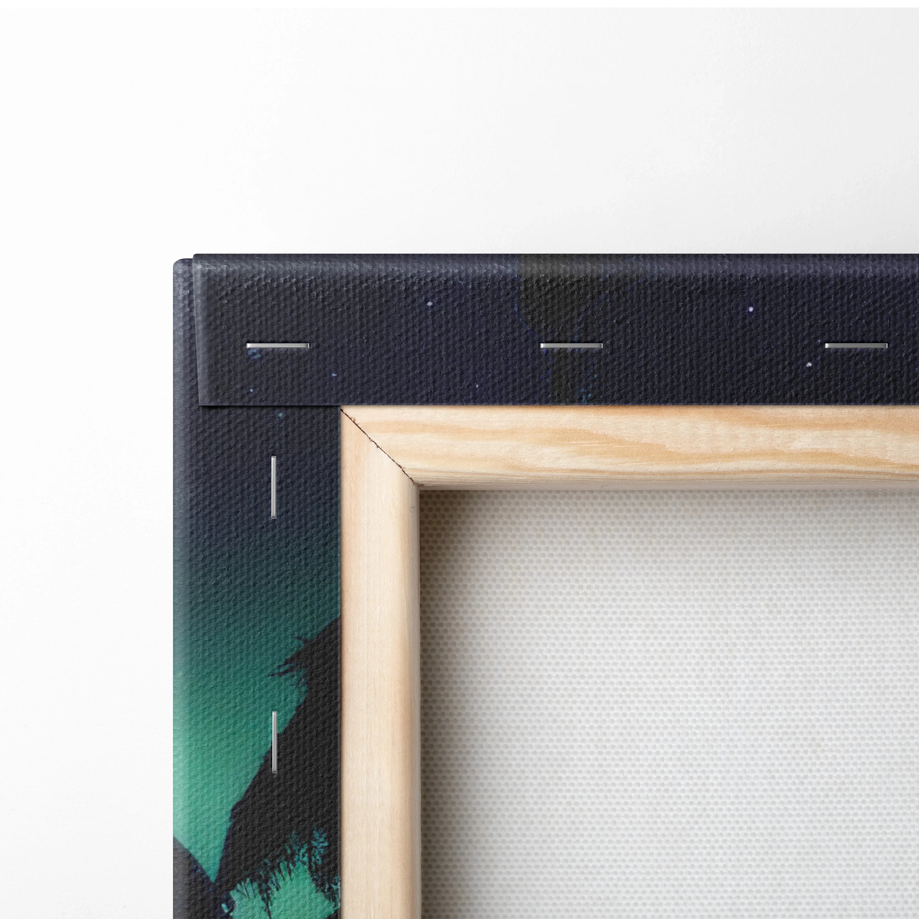 Canvas wall art corner with wooden frame and staples, showing dark forest and northern lights colors.