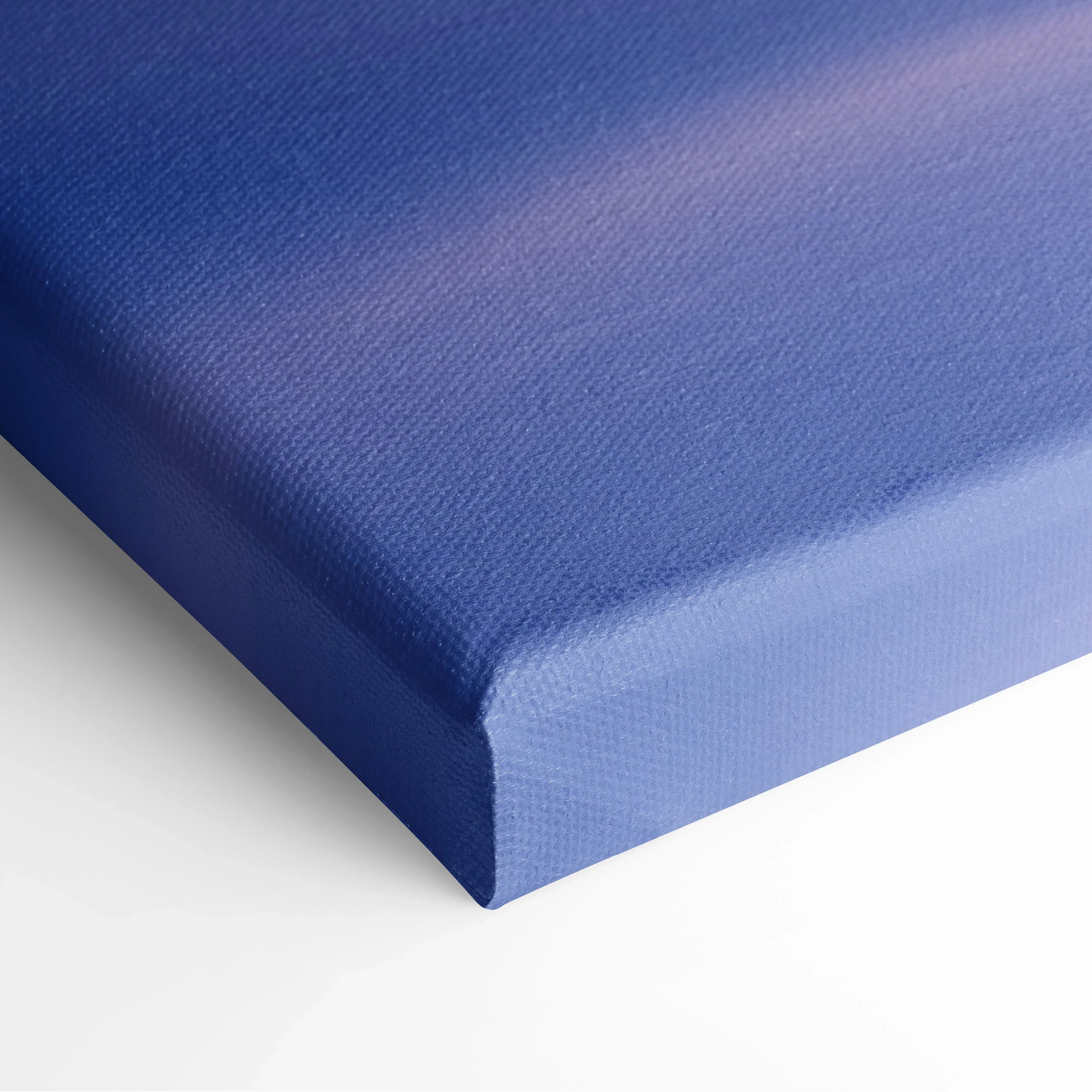 Close-up of stretched canvas with deep blue edge wrapping and fine textured surface for wall art decor.