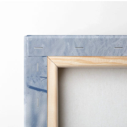 Close-up of wrapped canvas corner with natural wood frame and light blue printed edge for wall art decor.