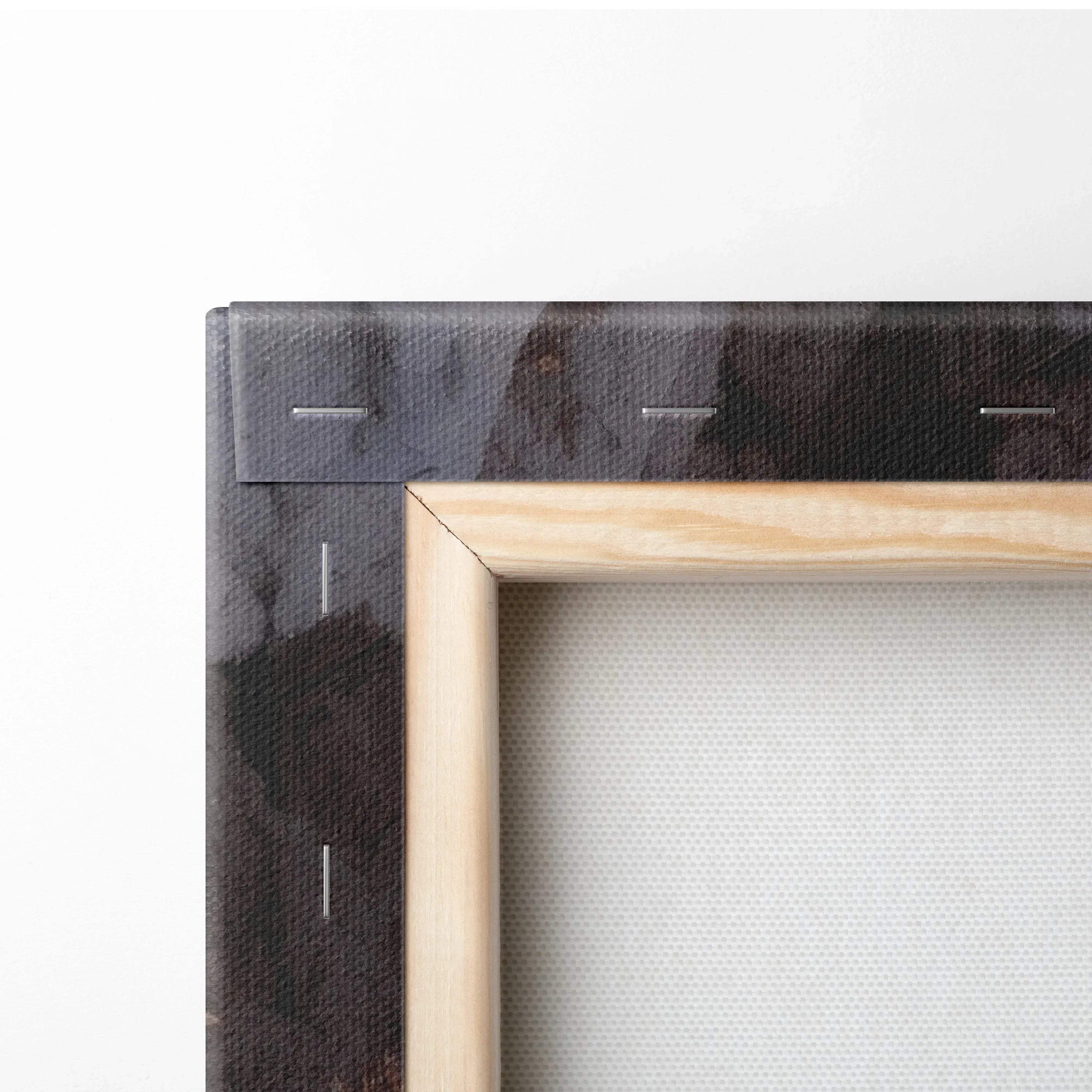 Close-up of a wooden stretcher frame with folded black canvas edge, showing textured fabric and stapled corners.