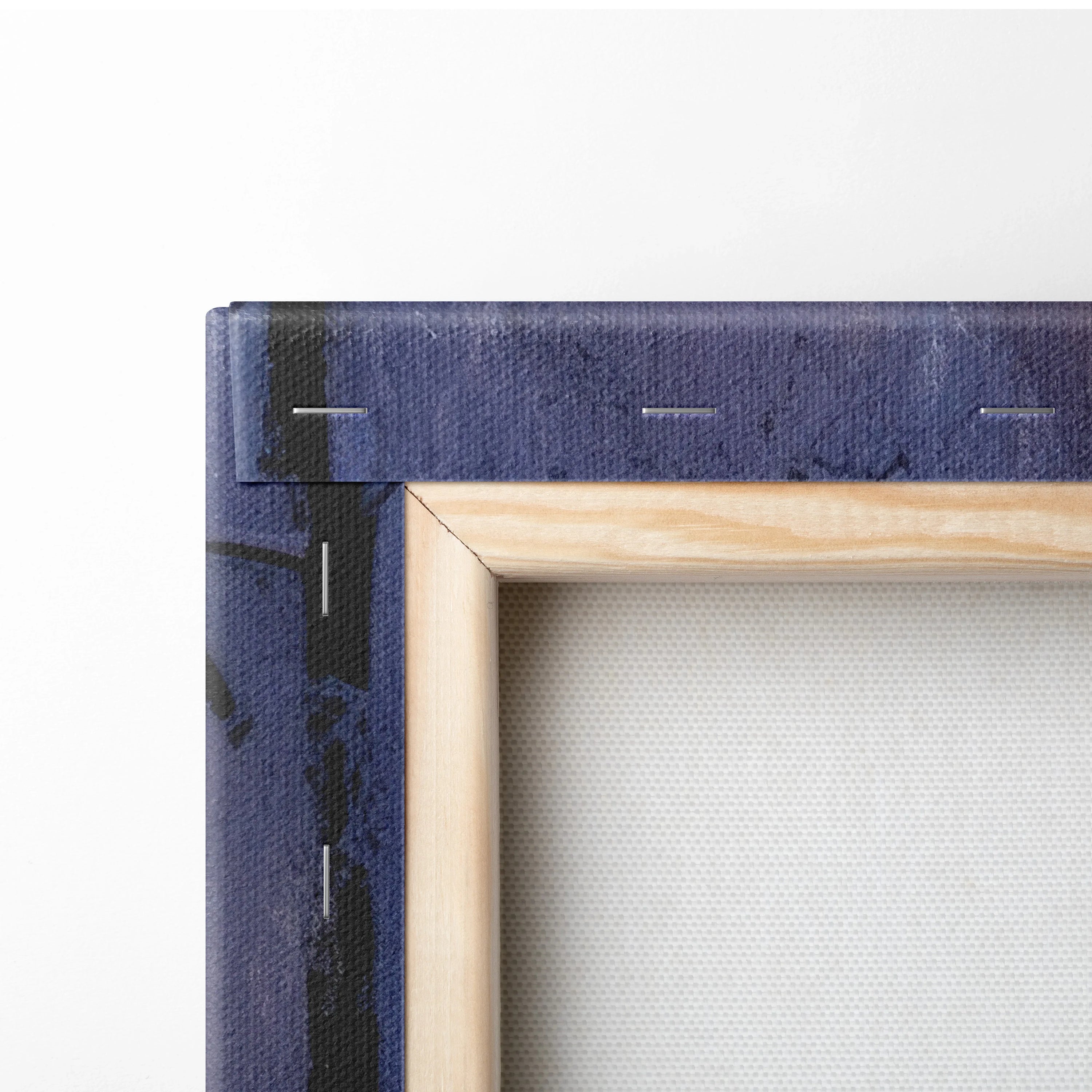 Close-up of wooden frame corner with stretched white canvas and part of dark blue printed canvas wrap edges for wall art.