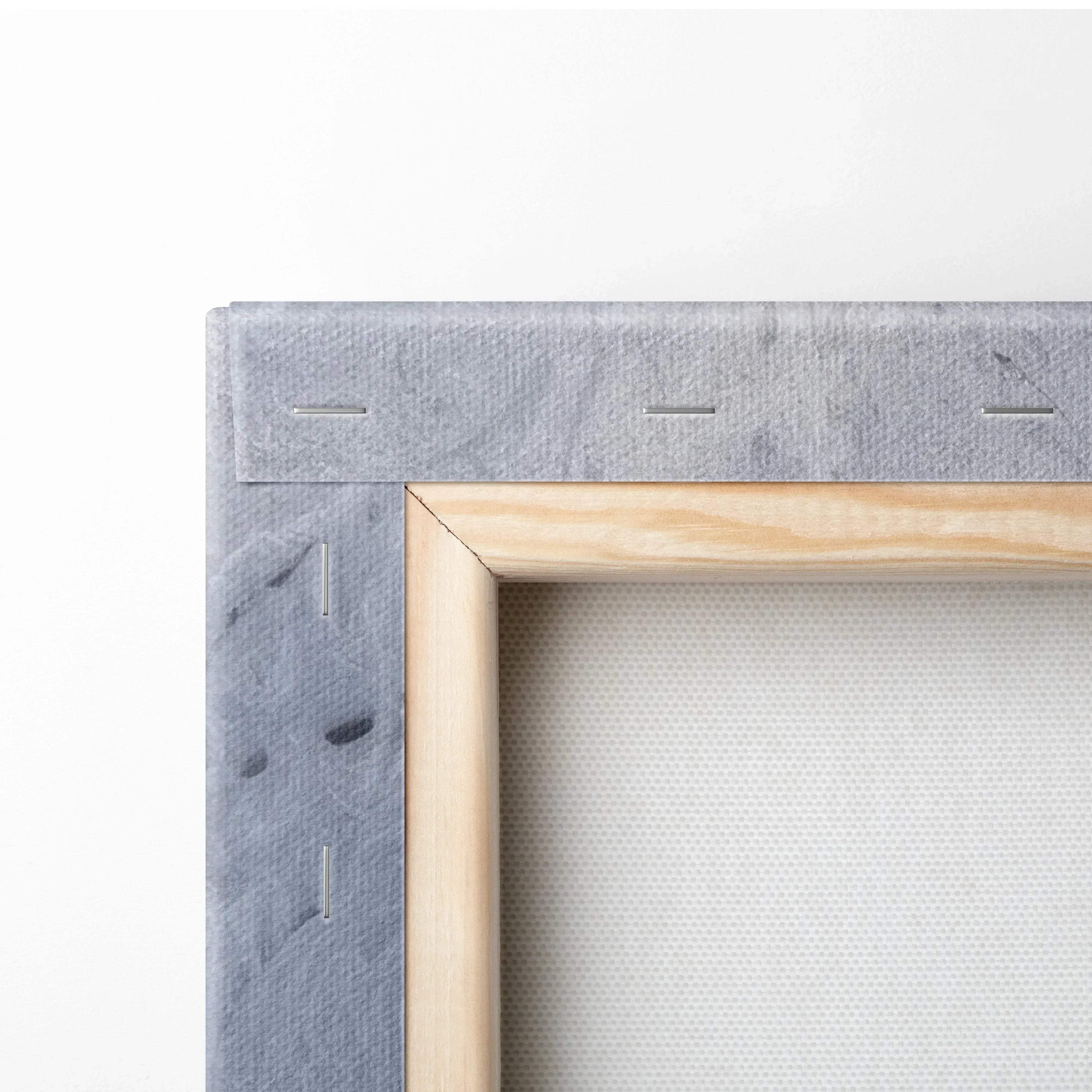Close-up of stretched canvas with light wood frame and gray textured fabric backing for wall art decor.