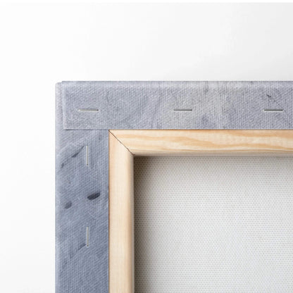 Close-up of stretched canvas with light wood frame and gray textured fabric backing for wall art decor.
