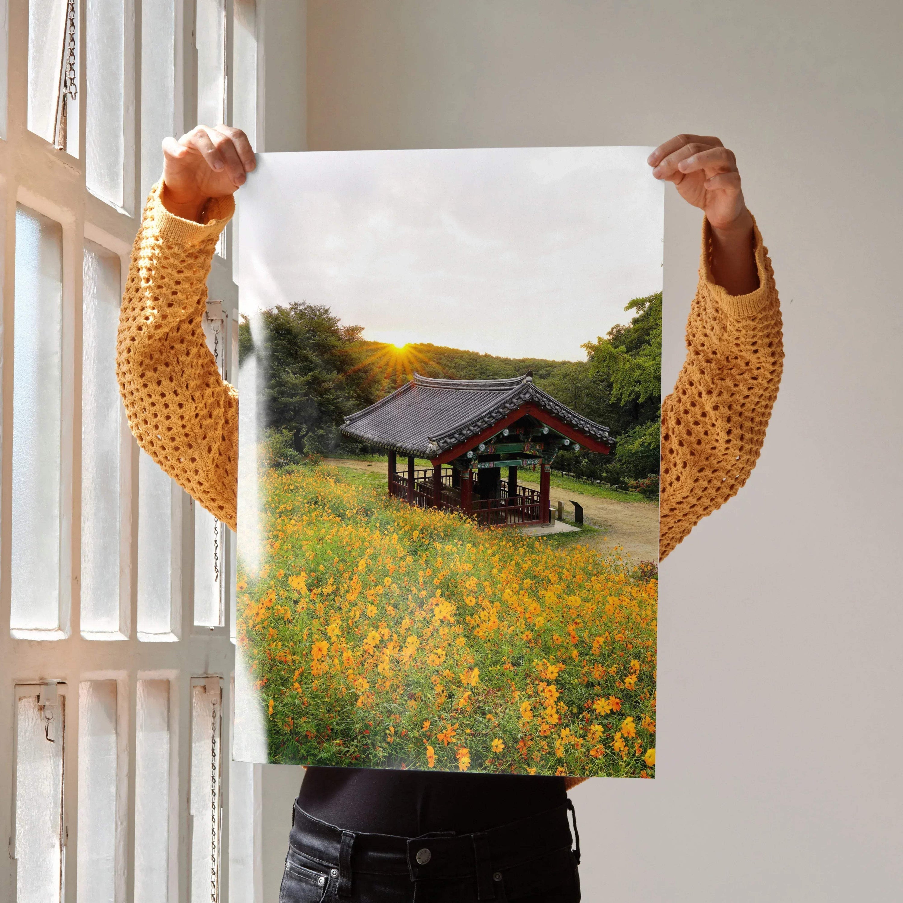 Vertical wall art poster featuring a rustic building surrounded by yellow floral field at sunset.