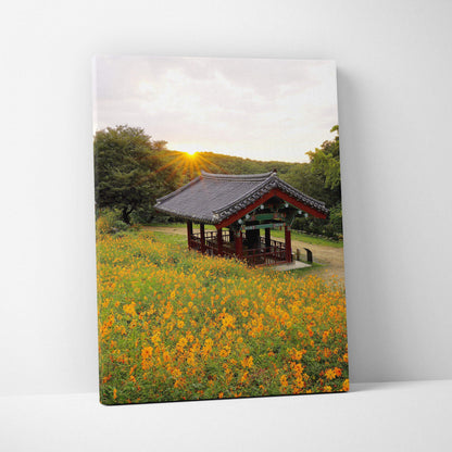 Canvas wall art featuring a traditional pavilion amid vibrant yellow flowers at sunset.